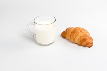 Glass cup with milk and croissant