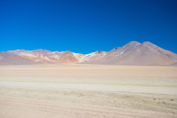 Sandy desert stretch and volcano on the Bolivian Andes