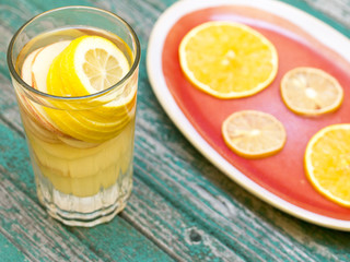 Detox water with lemon and apple in a glass on a wood background