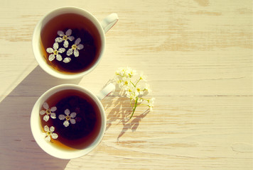 Two cups of tea and spring flowers on a wooden background