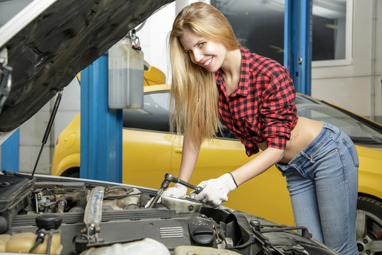 Beautiful girl mechanic repairing a car
