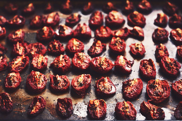 Homemade dried tomatoes with thyme and rosemary on a baking shee - obrazy, fototapety, plakaty