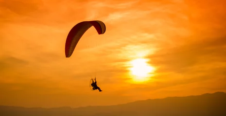 Tableaux sur verre Sports aériens Silhouette paraglider on sunset