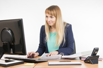 Office employee working at the computer and a folder of paper documents