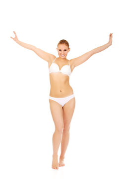 Happy young woman in white underwear holds her arms up