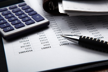pen on background of calculator and accounting papers