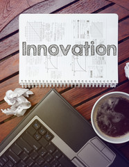 work place - table with notebook with note about: innovation