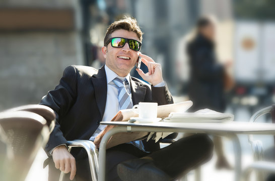 businessman in sunglasses having breakfast coffee early morning reading newspaper news talking on mobile phone