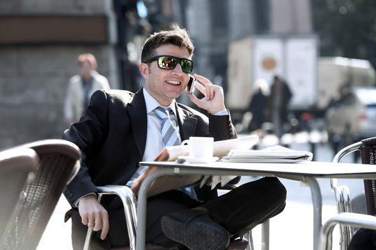 businessman in sunglasses having breakfast coffee early morning reading newspaper news talking on mobile phone