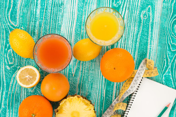 citrus fruits - lemon, grapefruit, orange, pine apple and measuring tape and jotter on  turquoise...