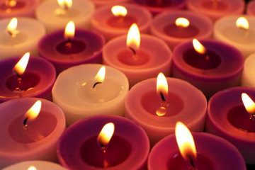 Fototapeta na wymiar Many burning small candles on dark background, close-up