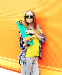Fashion pretty girl wearing a sunglasses with skateboard over co