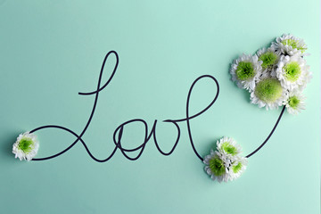 Inscription love with white flowers on green background