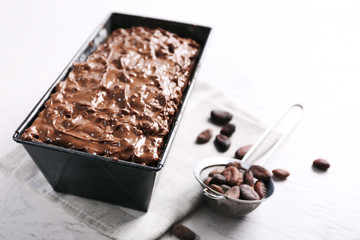 Delicious chocolate cake with nut cream in pan on white wooden table, close up
