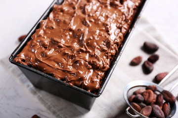 Delicious chocolate cake with nut cream in pan on white wooden table, close up