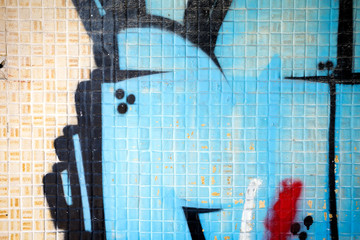 détail d'un graffiti bleu, noir, rouge peint sur des carreaux de carrelage 