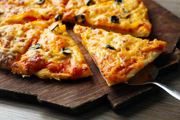Delicious sliced pizza on wooden board, close up
