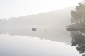 beautiful misty morning view of the calm tranquil sea with reflections of the surroundings in the...