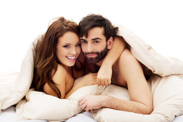 Beautiful couple under the cover in their bed.