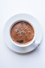 White cup of coffee on white table. Top view