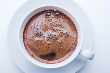White cup of coffee on white table. Top view