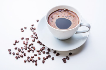 White cup of coffee with coffee beans on white table