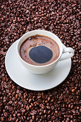 White cup of coffee on coffee beans