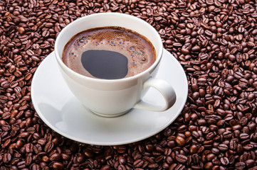 Naklejka premium White cup of coffee on coffee beans