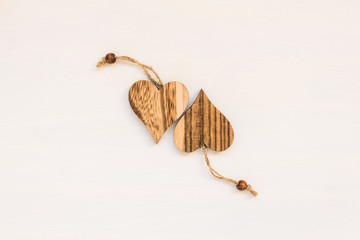 Two wooden hearts on white background with string