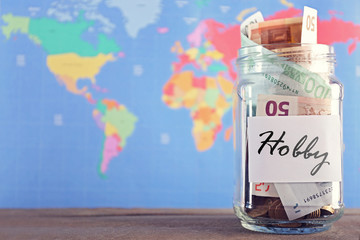 Savings for trip in glass bank on colourful map background