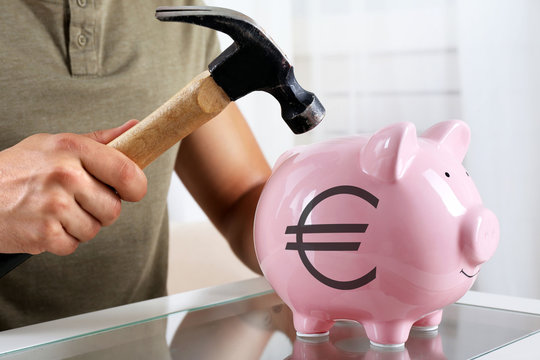 Man with a hammer going to break the piggy bank, close up
