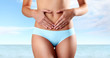 woman hands heart shape on belly, isolated on blue sky and sea