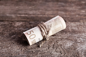 Roll of Euro banknotes on wooden background