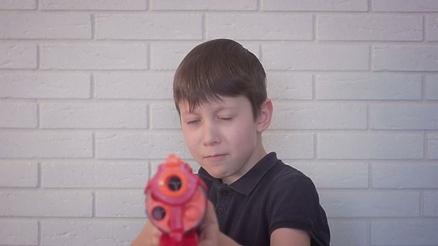 Young boy with toy gun game shoots in the camera