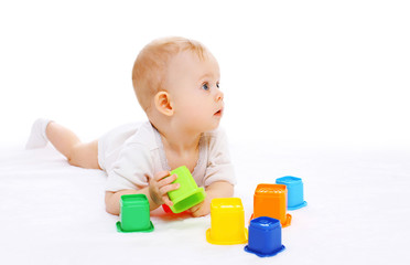 Cute baby lying playing with toys on white background