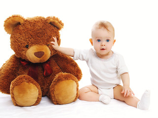 Cute baby sitting with big teddy bear on white background