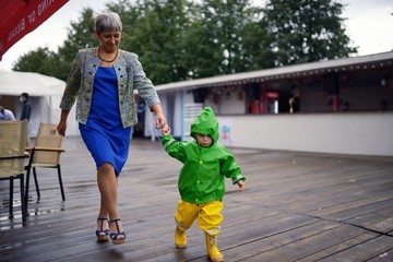 Happy little boy in not getting wet clothes together with grandmother