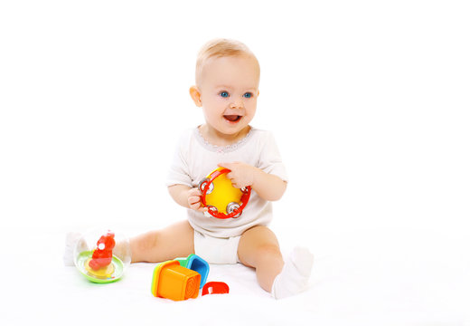Happy smiling baby playing with toys on white background