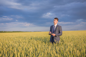 Naklejka na ściany i meble Businessman on a wheat field 