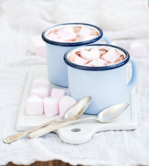Fototapeta na wymiar Seint Valentine's holiday greeting set. Hot chocolate and heart shaped marshmallows in old enamel mugs on white ceramic serving board 