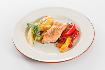 Grilled salmon fillet with vegetables, spices and arugula on a plate