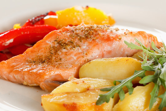 Grilled salmon fillet with vegetables, spices and arugula on a plate