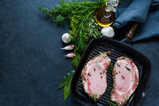 Pork lion steaks on frying pan, dark slate background