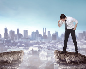 Business person looking down from top of the cliff