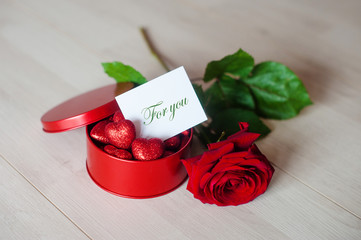 Red tin box with red hearts with a note for you and a red rose on a white background