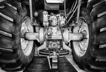 Large rear tractor tires connected by an axle in black and white