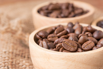 Various types of coffee beans in the wood bowl on the wooden table