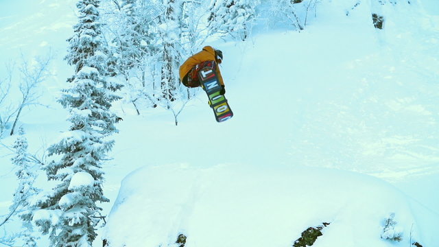 Man on snowboard jumping from the hill and falling in the snow