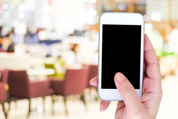 Hand holding smart phone over blur restaurant background