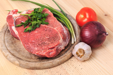 Slice of meat on the cutting board with spices, onion, garlic an